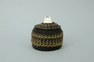 Image: round baleen basket woven in two colors with walrus head finial;
